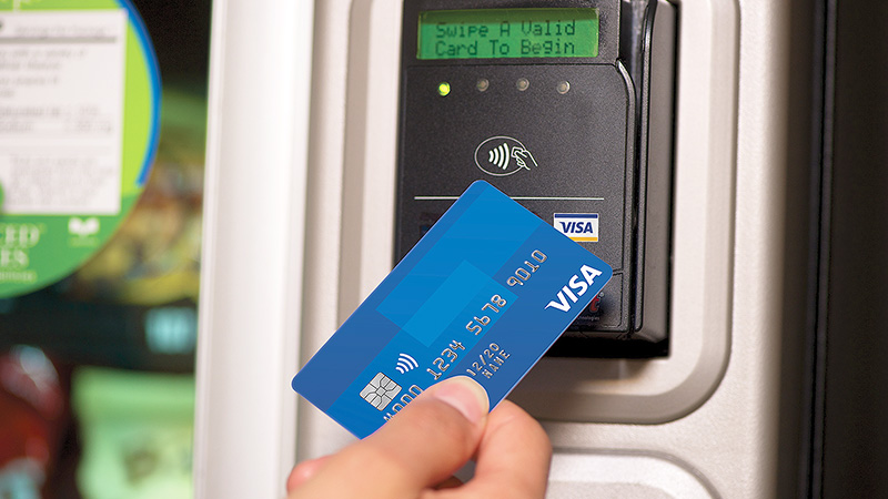 Person tapping contactless Visa card on contactless enabled payment terminal.