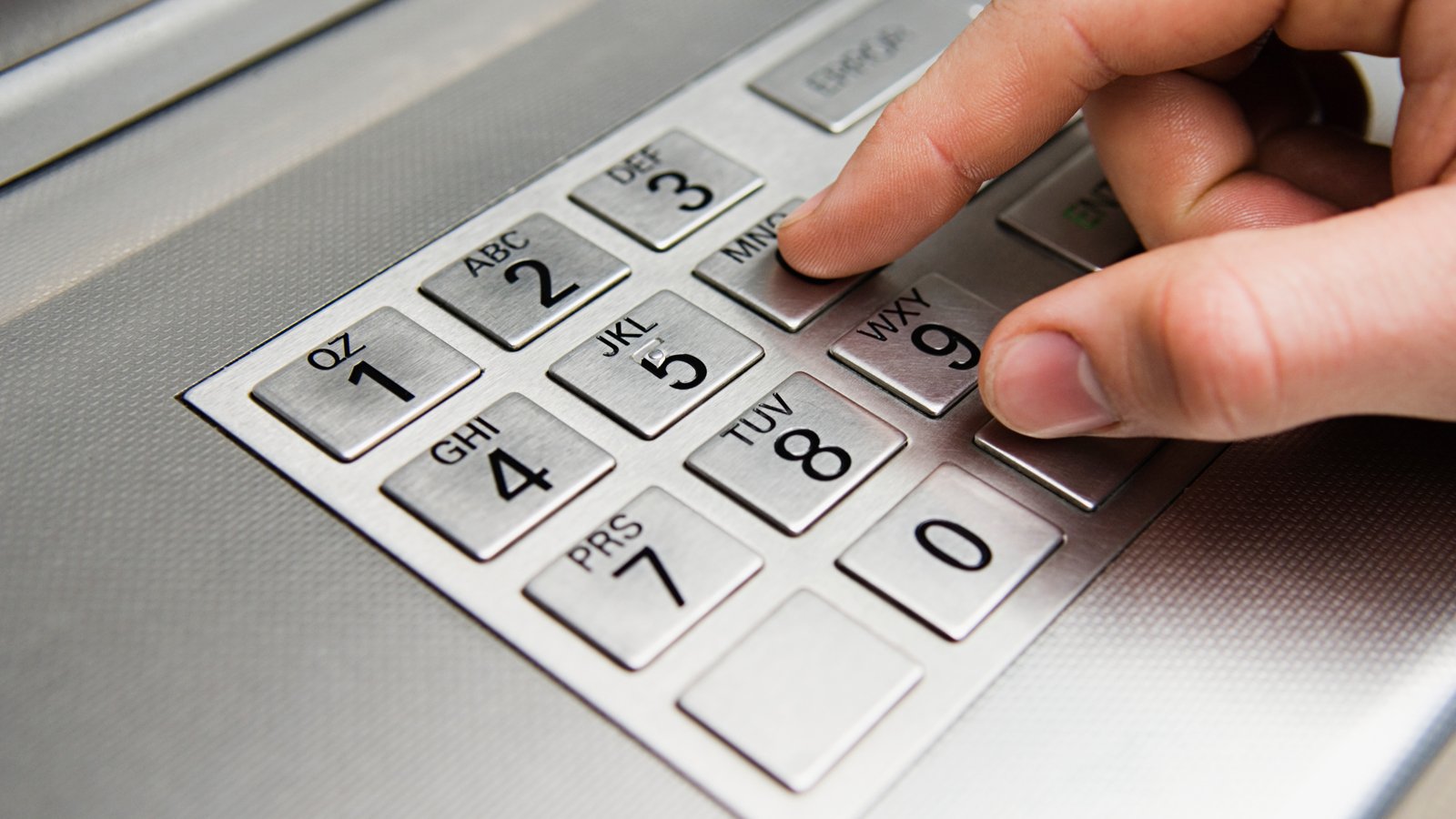 Hand at ATM keyboard.