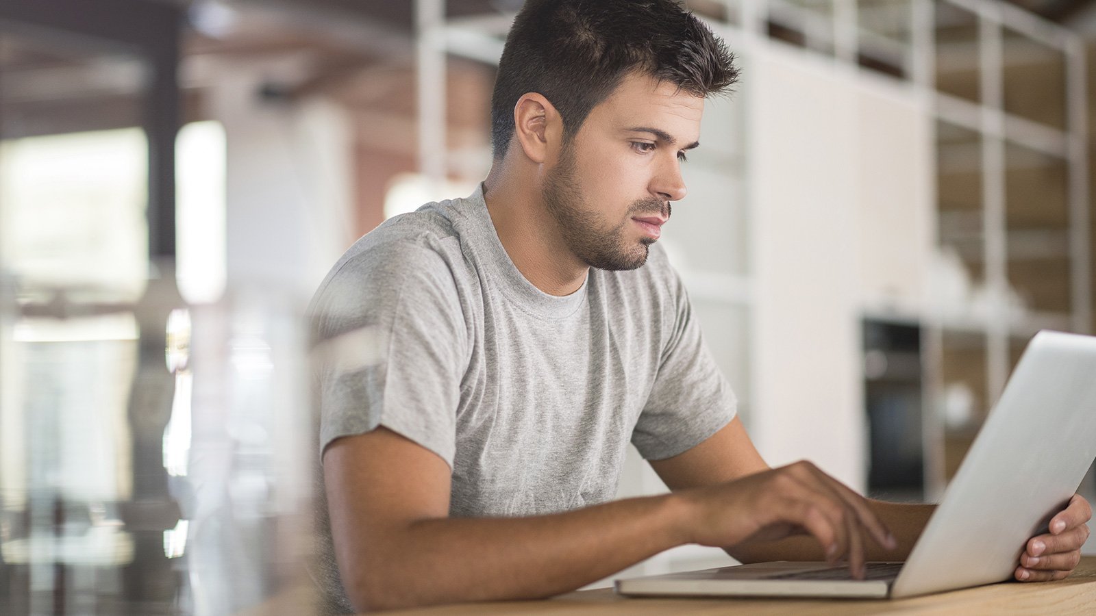 Seated man using laptop at home.