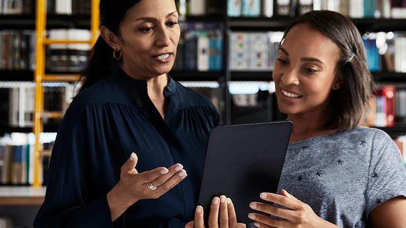 Two women holding a tablet having a discussion