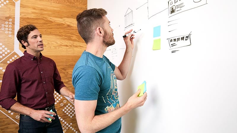 Two men engage in teamwork as they brainstorm and plan on the Visa small business hub.